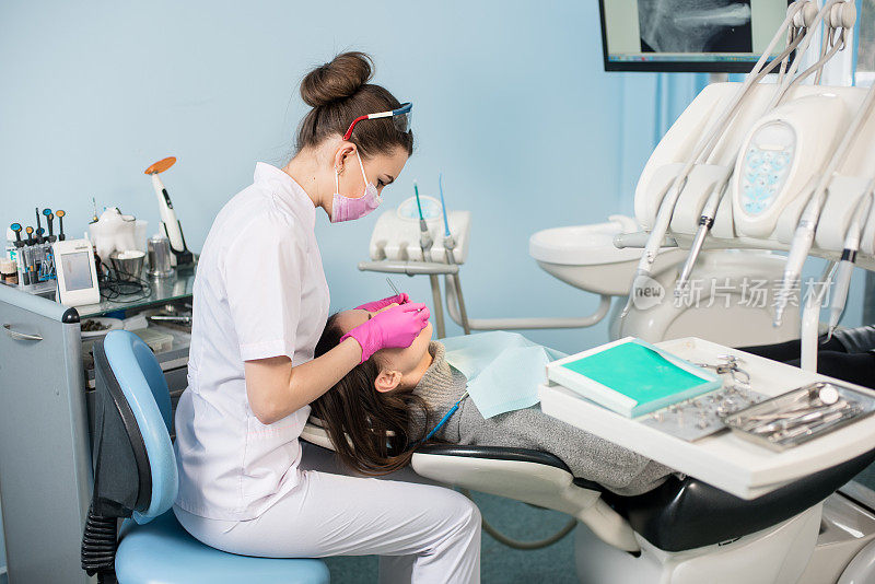 女牙医带着牙科工具-镜子和探针在牙科诊所检查病人的牙齿。医学、牙科和保健概念。牙科设备