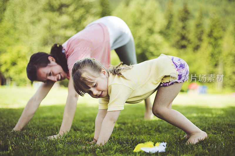 瑜伽教练和小女孩在公园里练瑜伽。