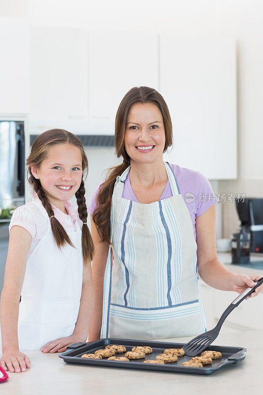 女孩和妈妈在厨房准备饼干的肖像