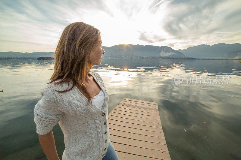 年轻女子在湖边码头休息，看风景