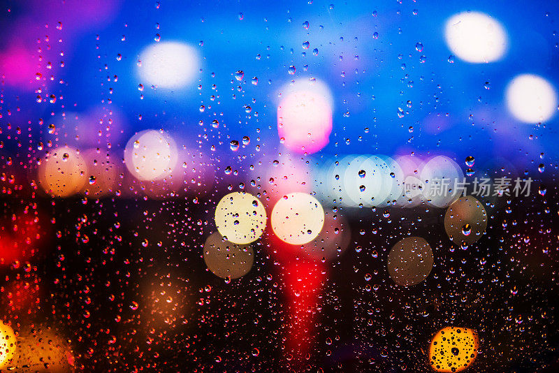 夜晚的城市灯光透过雨滴透过窗户