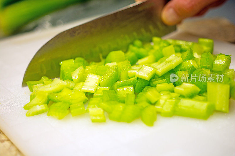 用锋利的刀把芹菜切成小块放在白色砧板上