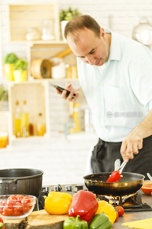 男人一边做饭一边用手机