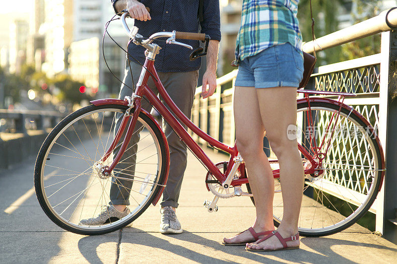 在城市里，成年人站在一辆自行车旁