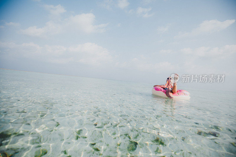 性感的女人浮在水上，有鸡尾酒时间在海洋，马尔代夫