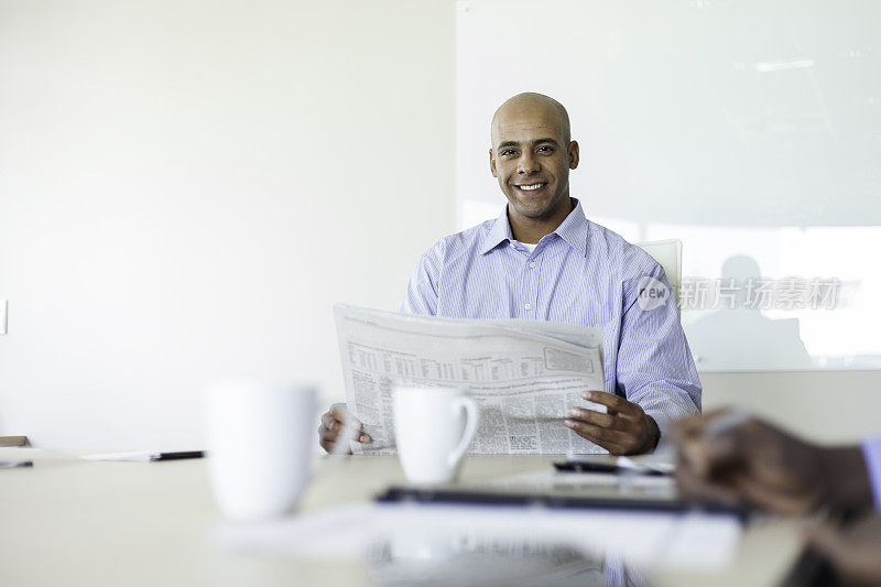 一个非洲商人坐在会议室里看报纸