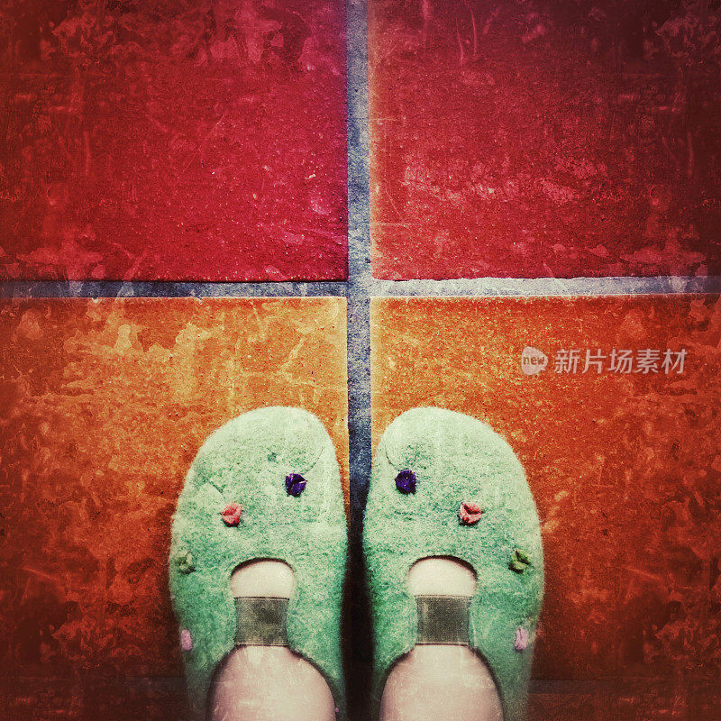穿着绿色拖鞋的脚，踩在粗糙的瓷砖地板上