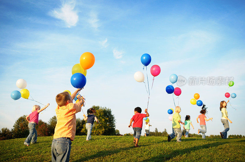 一群孩子拿着气球在阳光下奔跑