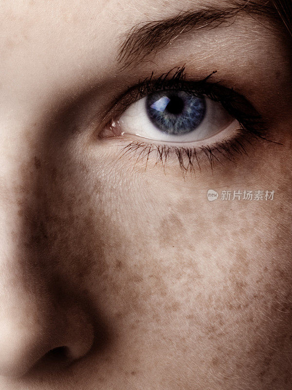 女人的蓝眼睛和她脸颊上的雀斑的特写