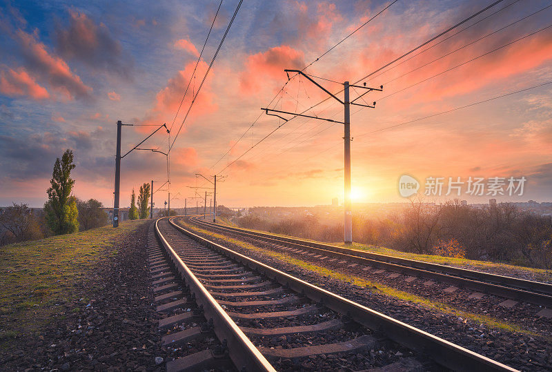 铁路和美丽的日落天空。工业景观有火车站，五颜六色的蓝天和红云，树木和绿草，夏天黄色的阳光。铁路枢纽。重工业