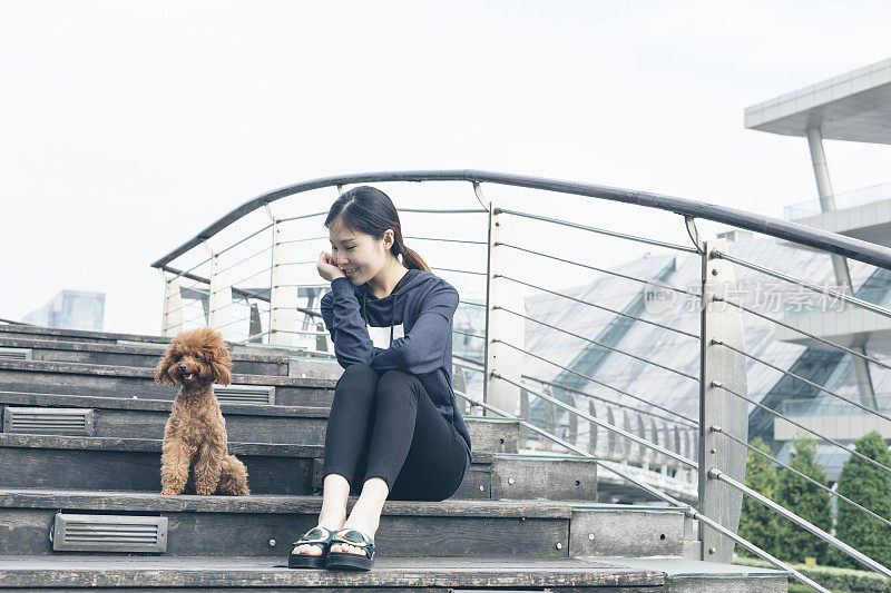 女人和小狗狗一起坐在桥上