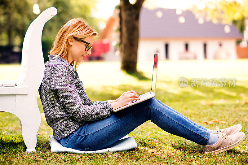 带着笔记本电脑在户外学习的年轻女子。