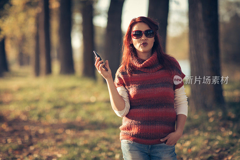 在秋天公园里用手机的女人