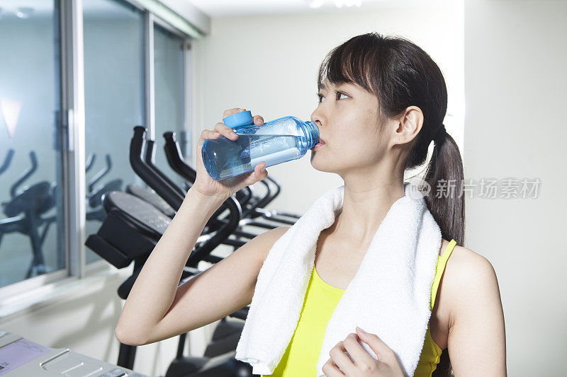 一个女人在健身房喝水。