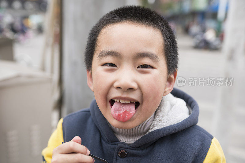 亚洲小学男孩吃果酱在街上高兴