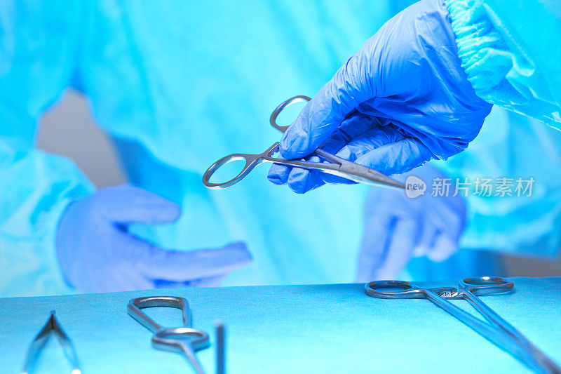 外科医生的双手在手术室工作的特写，色调为蓝色