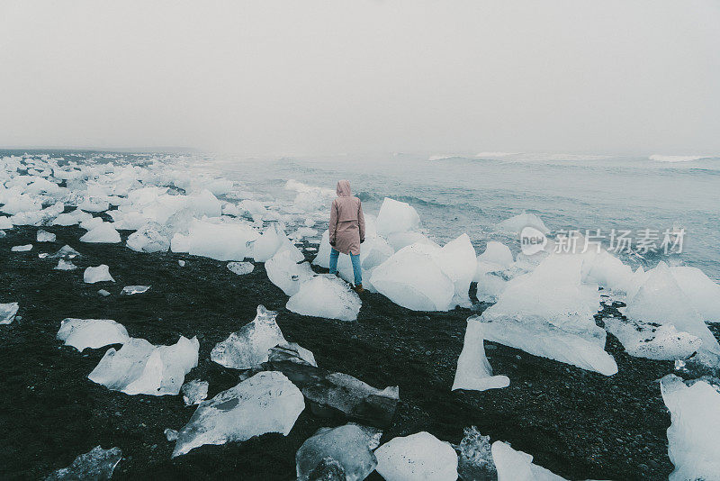 在Jokulsarlon附近被冰山覆盖的海滩上行走的女人