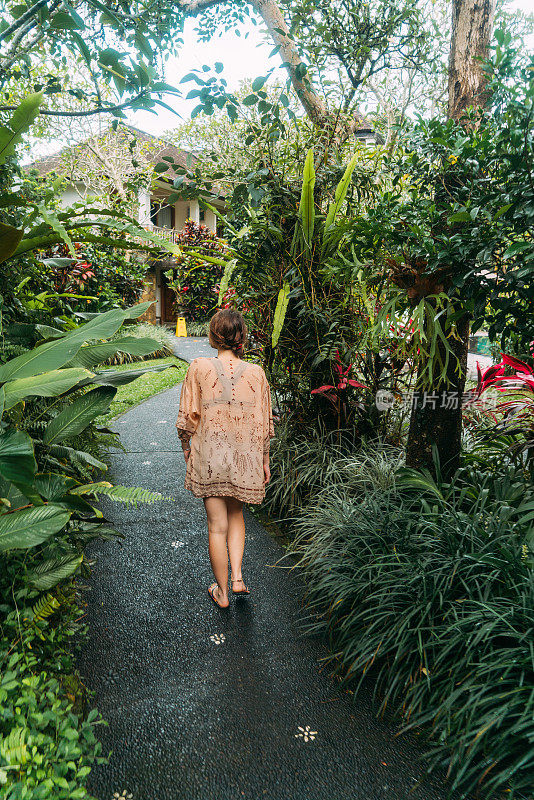 在热带花园里散步的女人