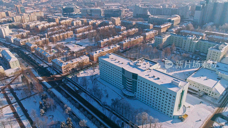 在晴朗寒冷的日子里，鸟瞰被雪覆盖的冬季城市全景。轨道摄影机运动。