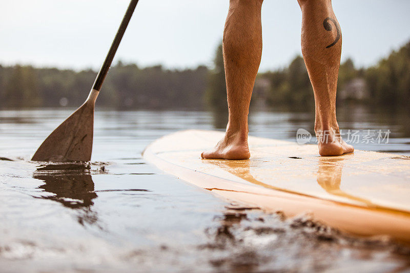 单口Paddleboard一同坐席。一个男人的腿的特写