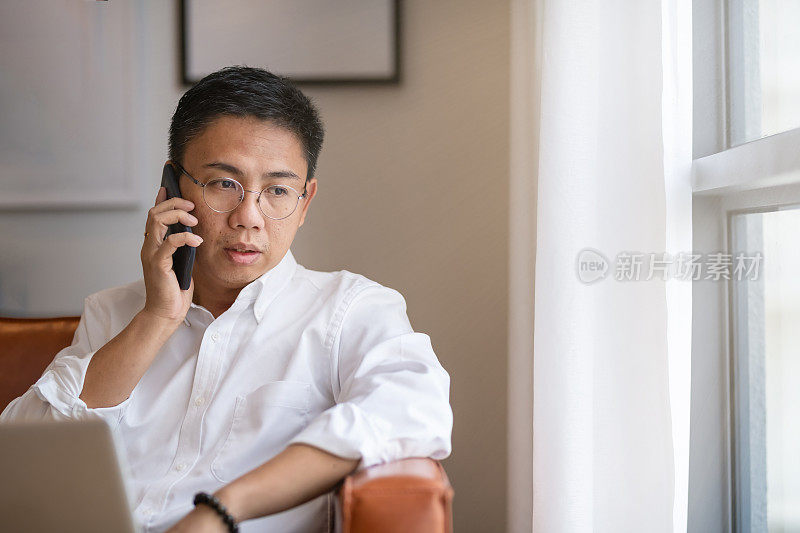 中年中国成年人在家工作，坐在沙发客厅里讲手机