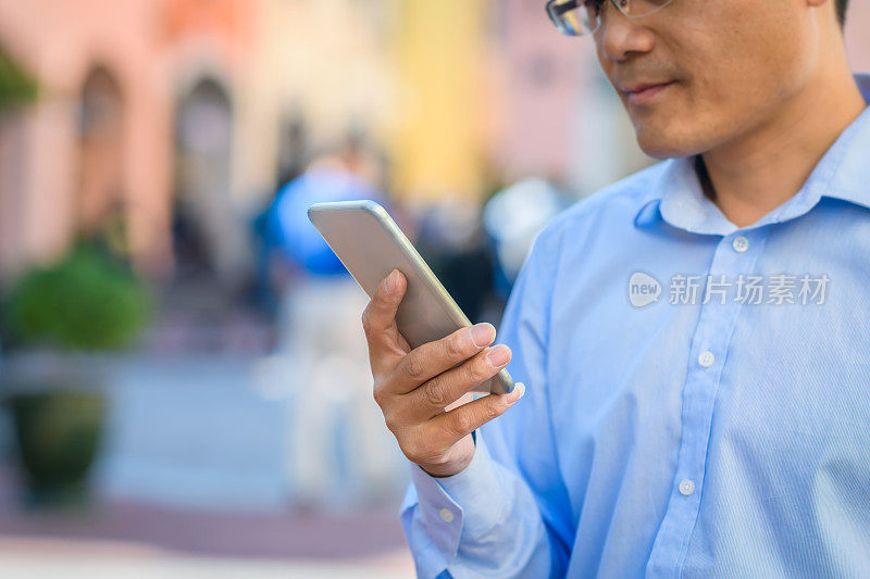 一位亚洲商人正在浏览智能手机。