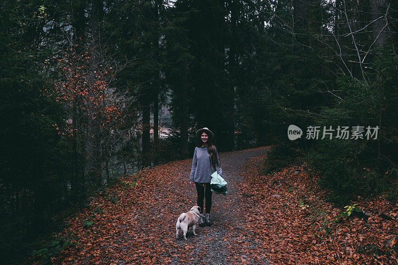 戴着帽子的女人带着狗在山林里散步