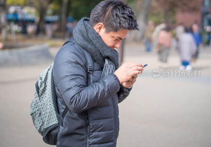 年轻的日本男子和亚洲朋友寻找旅游地点使用手机和花时间在日本一起