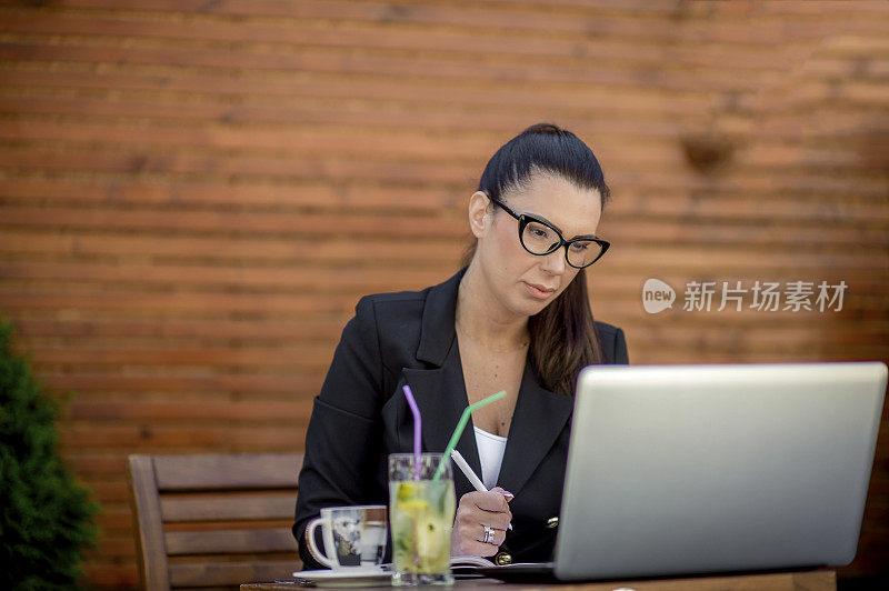 年轻的女商人在café用笔记本电脑工作