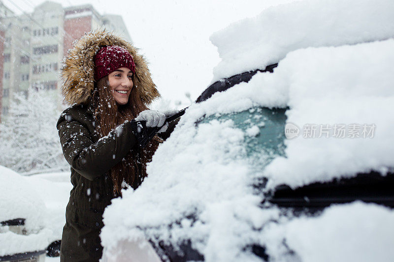 年轻女子在清理车上的积雪