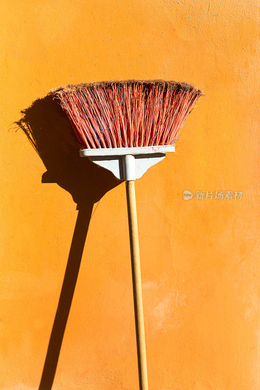 墨西哥尤卡坦半岛:红橙色的扫帚靠在明亮的橙色墙上