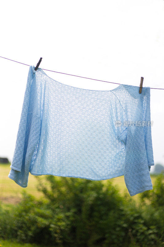 农村场景:女人在洗衣线上的淡蓝色毛衣