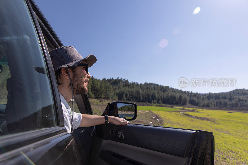 人从打开的车门和呼吸的公路上看自然