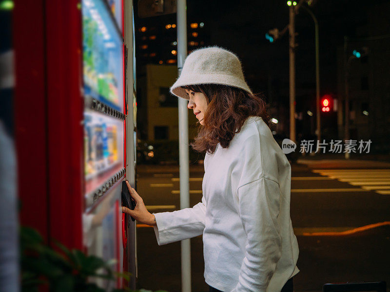 亚洲女人选择一些饮料在自动售货机