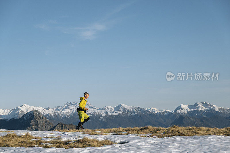 黎明时分，一名徒步运动员爬上雪山的山脊