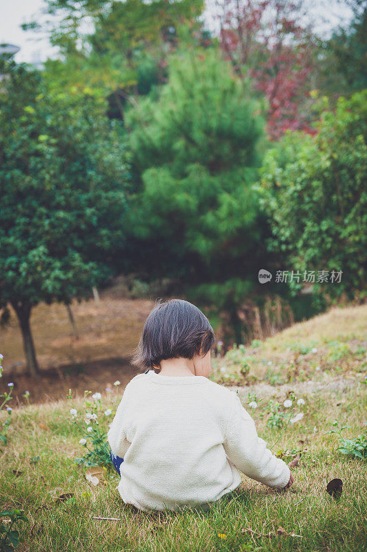 一个中国女孩坐在花园里的草地上