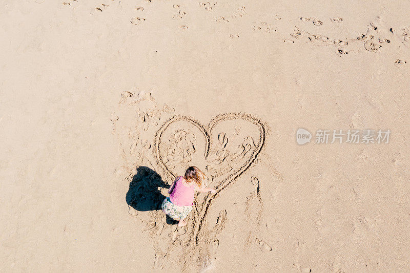 无人机的观点，年轻女子在海滩上画心