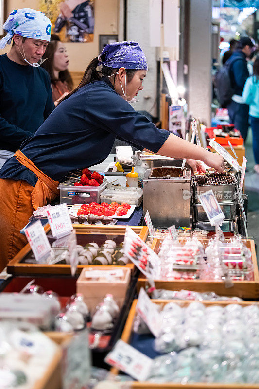 人们在京都西山市场与卖年糕、麻糬糖果的食品小贩一起服务