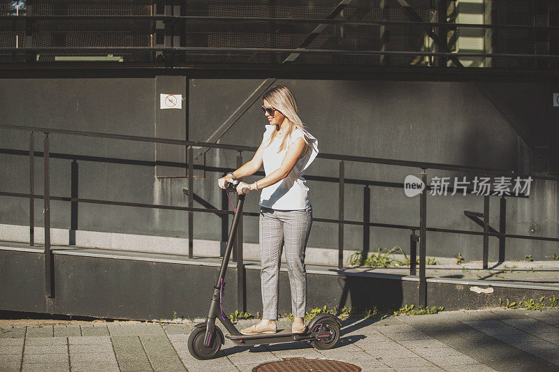 年轻的女商人在城市里骑摩托车