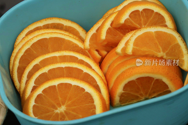 半片橙子堆在盒子里的图像，预先切好的柑橘类水果块用于酒精饮料