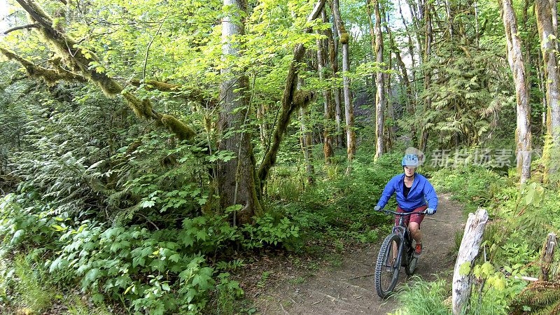 骑山地车的人骑着电动山地车沿着森林小径骑行
