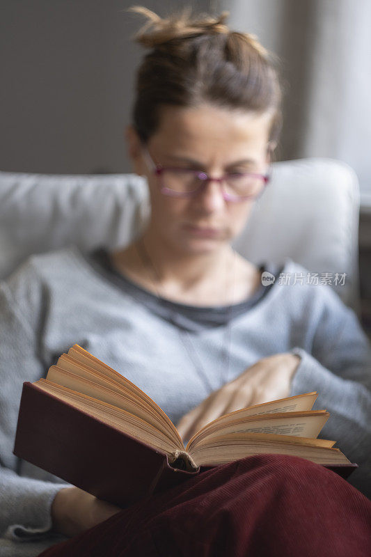 戴眼镜的女人在窗前看书