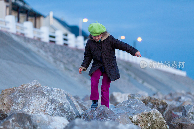 8岁的小女孩在黎明时分独自在法国海滩上爬岩石