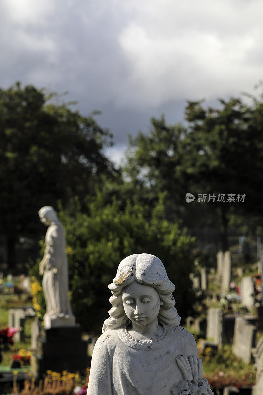 墓园天使雕像在阳光下暴雨后乌云密布