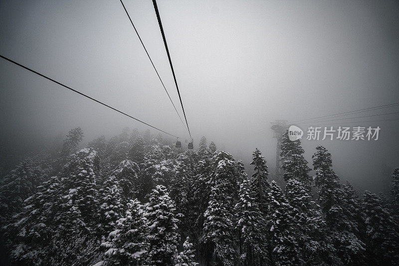 滑雪胜地的滑雪缆车，在暴风雪的雄伟背景下，白雪覆盖的斜坡和山脉