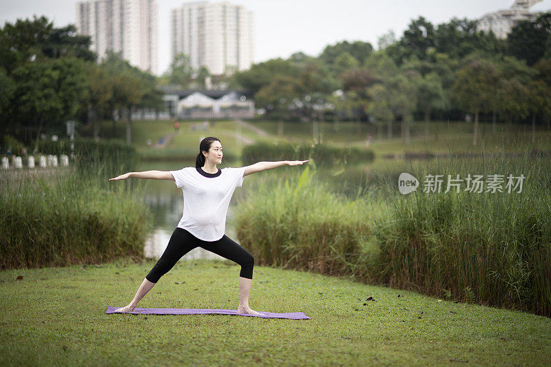 一名亚洲华裔孕妇在公园练习瑜伽