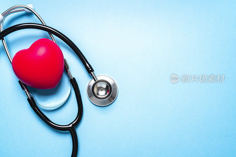 听诊器和蓝色背景上的红色心脏。本空间