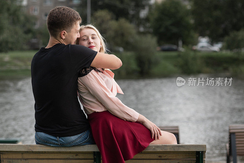 一对年轻夫妇坐在木凳上拥抱