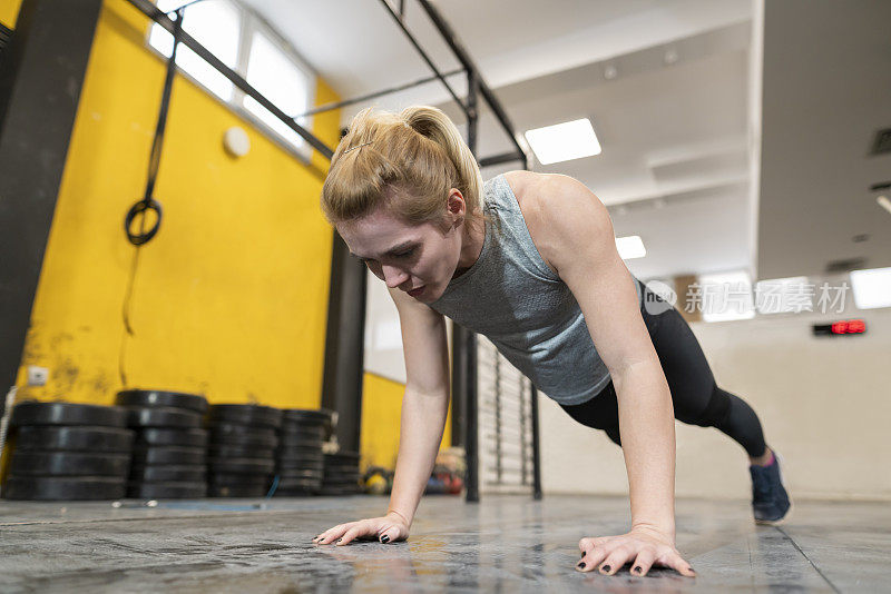 一个年轻的女运动员在健身房里做俯卧撑