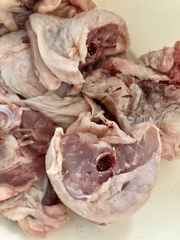 特写图像的塑料切菜板含有生肉，鸡腿上的骨头肉，准备好随时煮